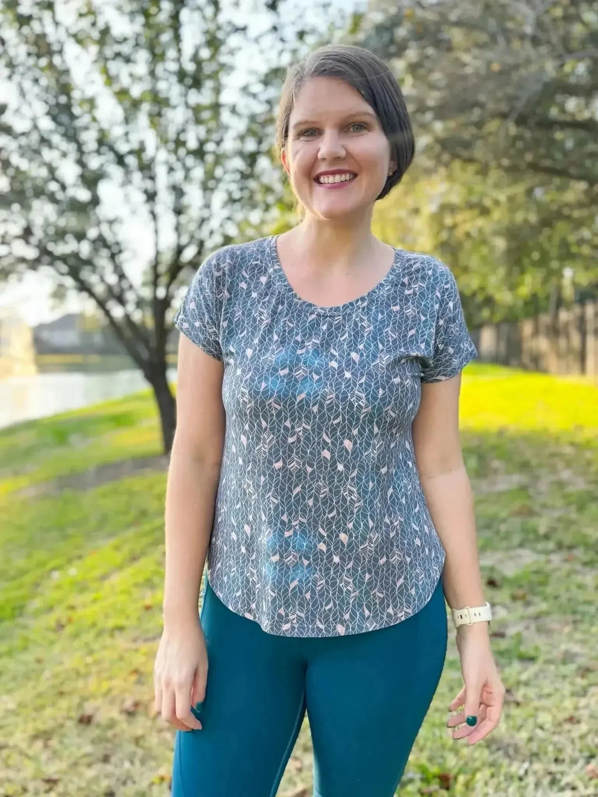 A woman wears a short-sleeved shirt with a gold leaf pattern print.