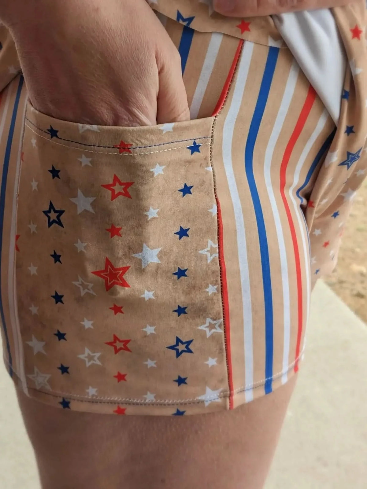 A person's hand is in the pocket of a garment with vintage stripes and stars.