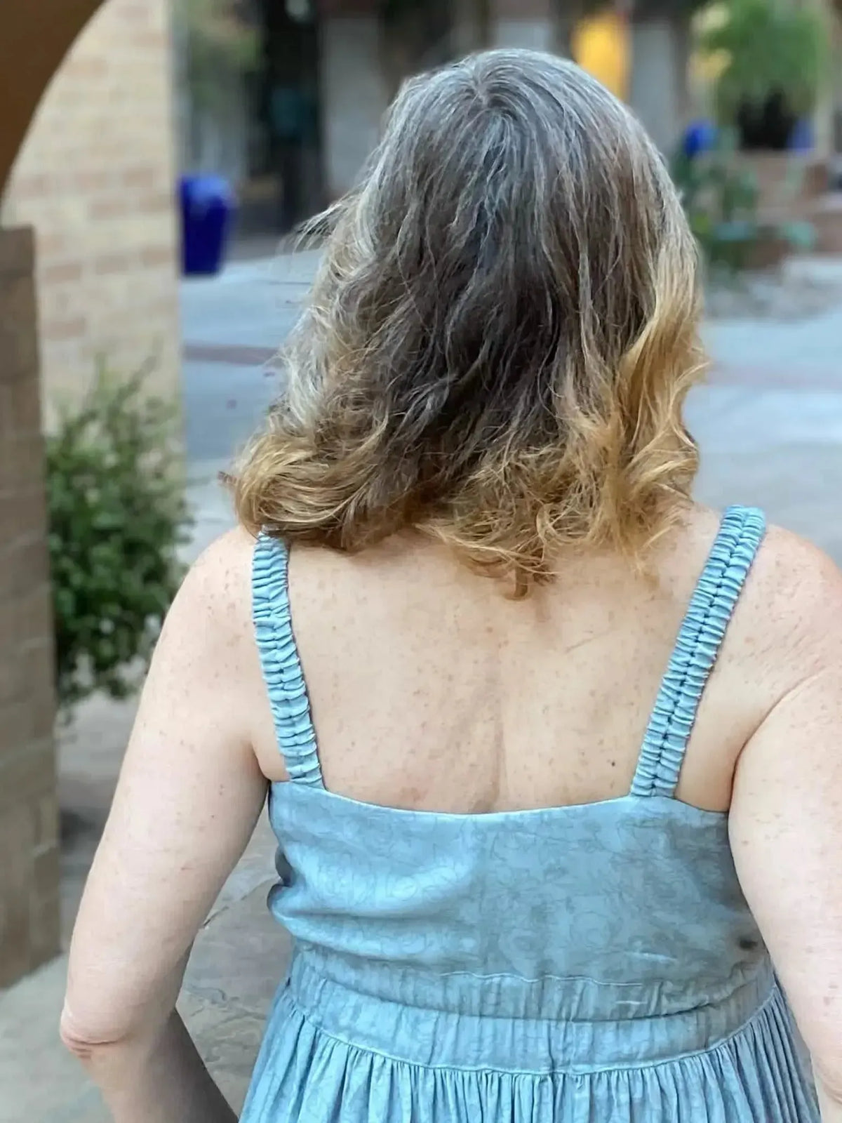 A woman from behind wearing a dusty blue stenciled floral dress.
