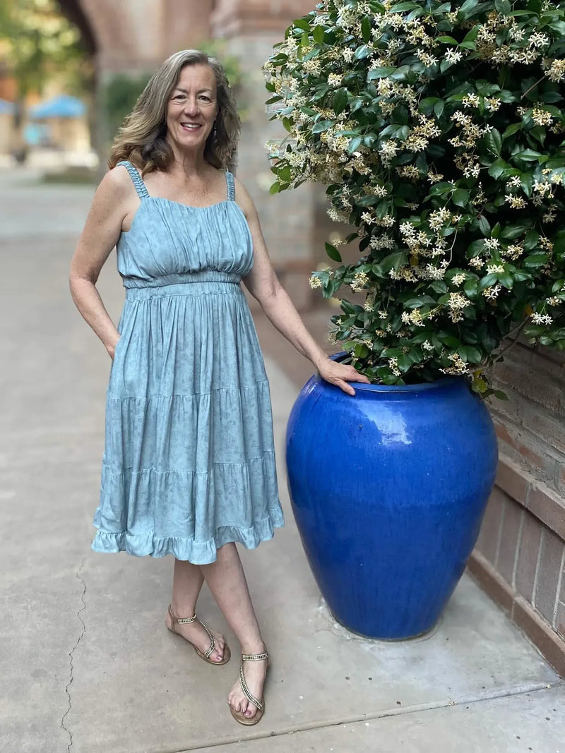 Dusty blue stenciled floral fabric on a woman wearing a dress.