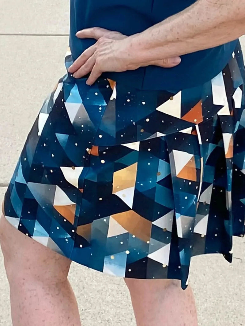 A person wearing a pleated skirt with a geometric pattern in blue, white, and orange.