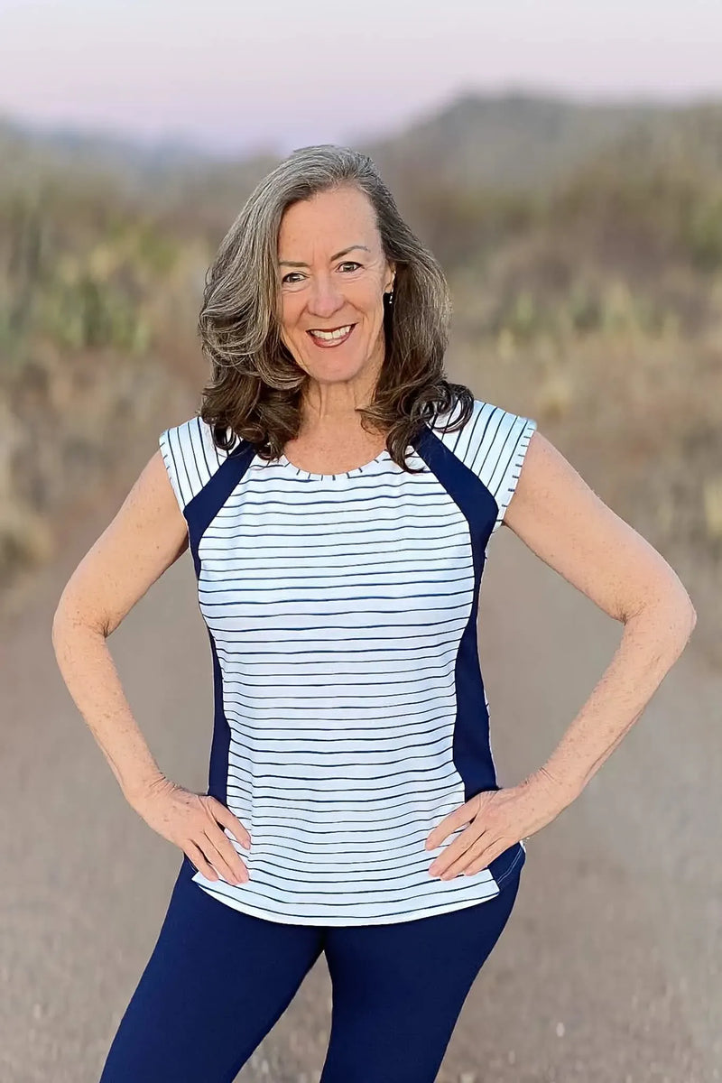 A smiling woman models a navy and white striped top with solid navy leggings.