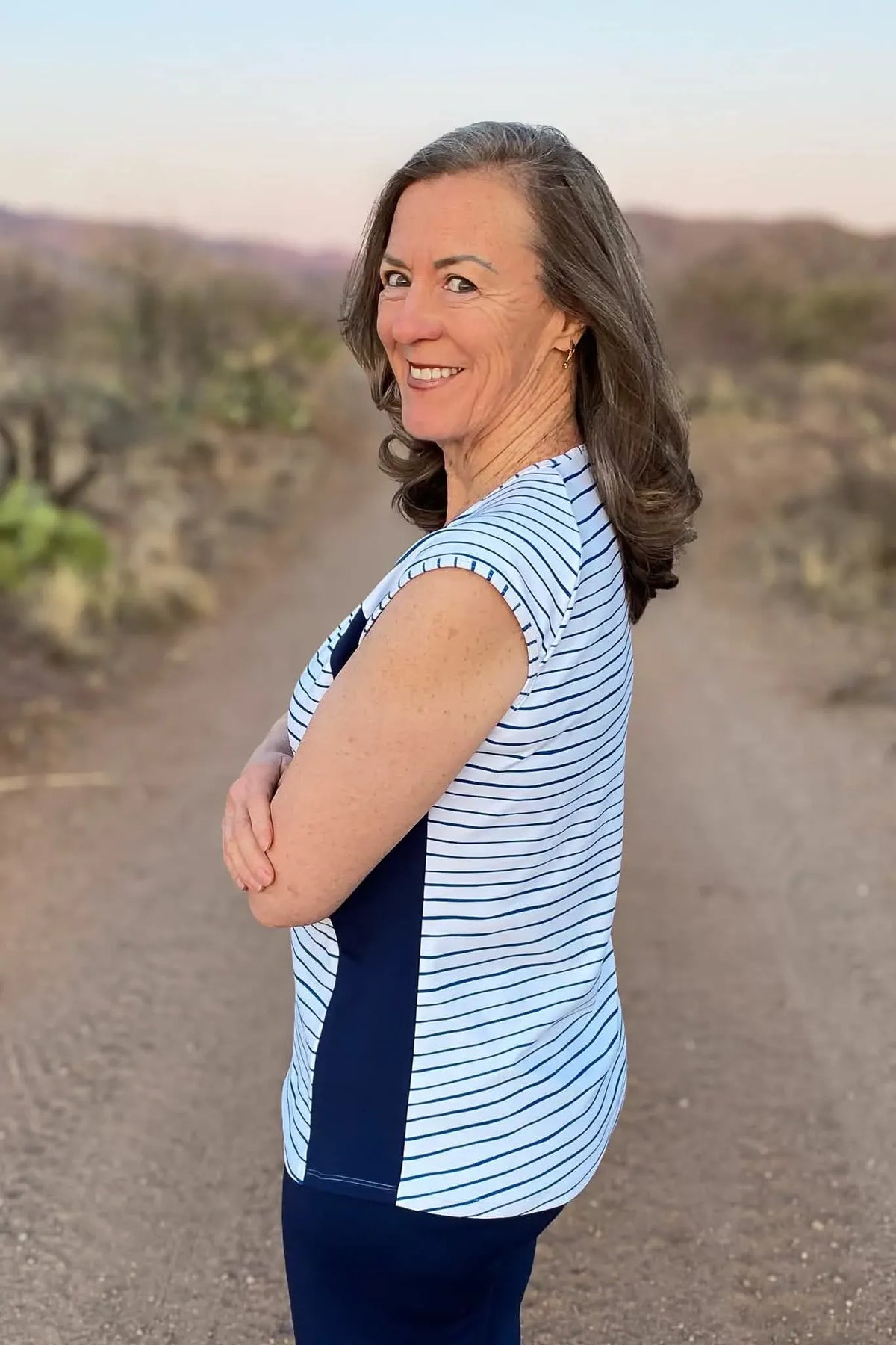 A woman in a navy and white striped top smiles at the camera.