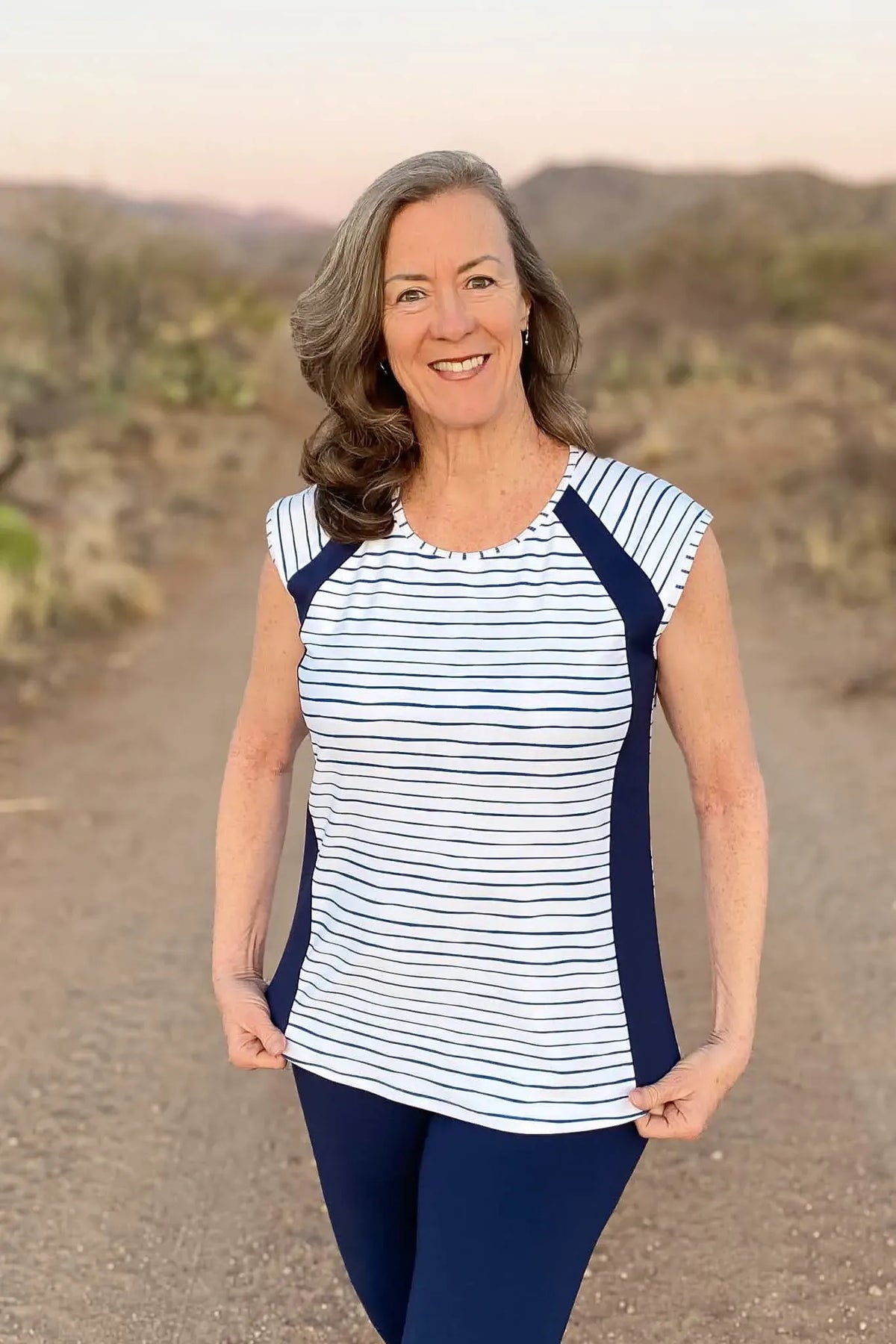 Woman in a white and navy striped top with navy leggings.
