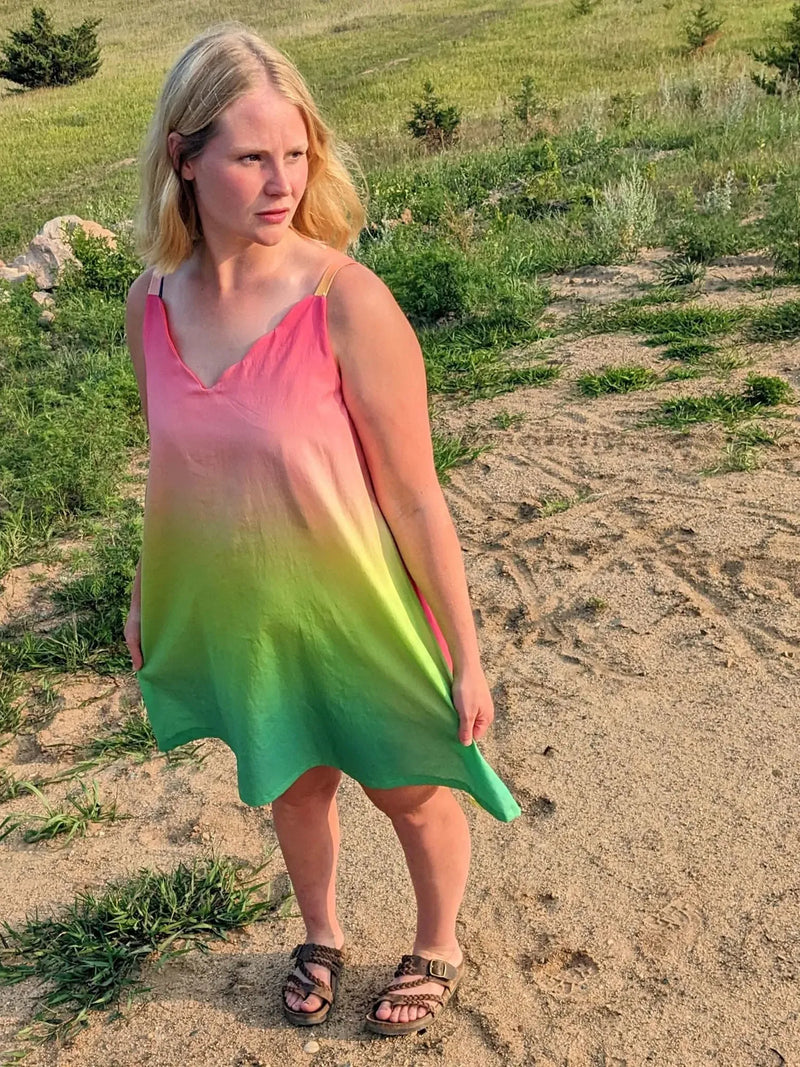 A woman wears a watermelon ombre dress with pink, yellow, and green hues.