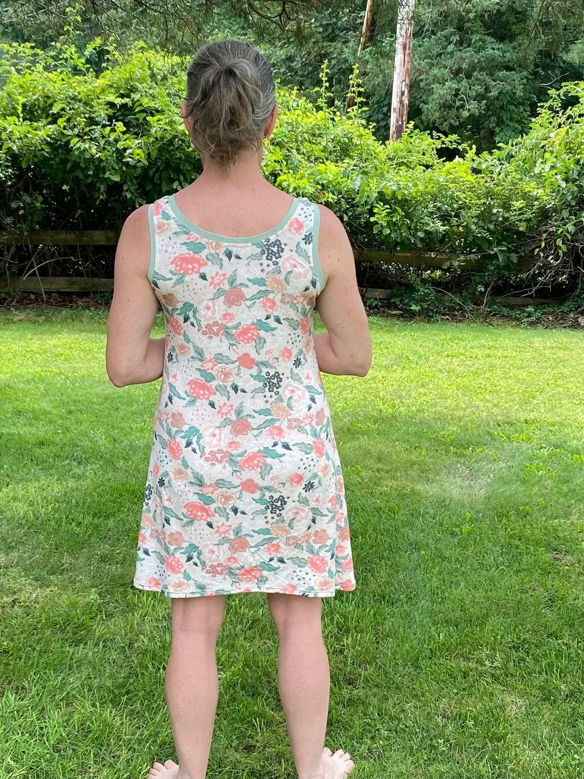 A woman from behind wears a floral dress with a light green trim.
