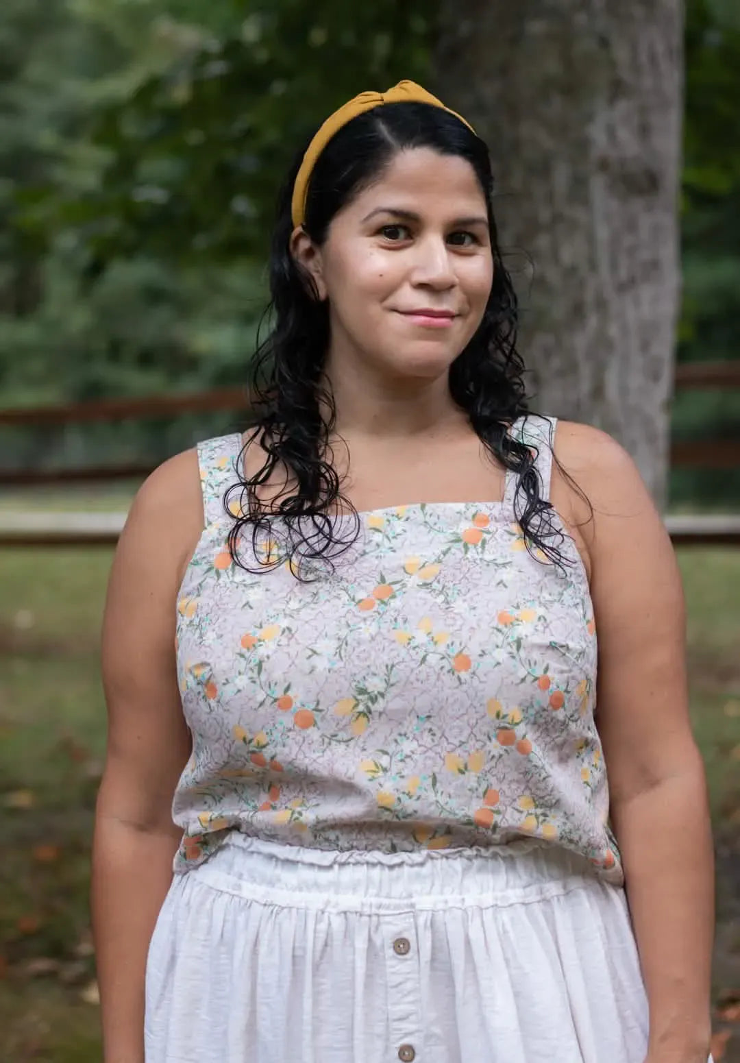 A woman wears a Moroccan Citrus print top and a white skirt.