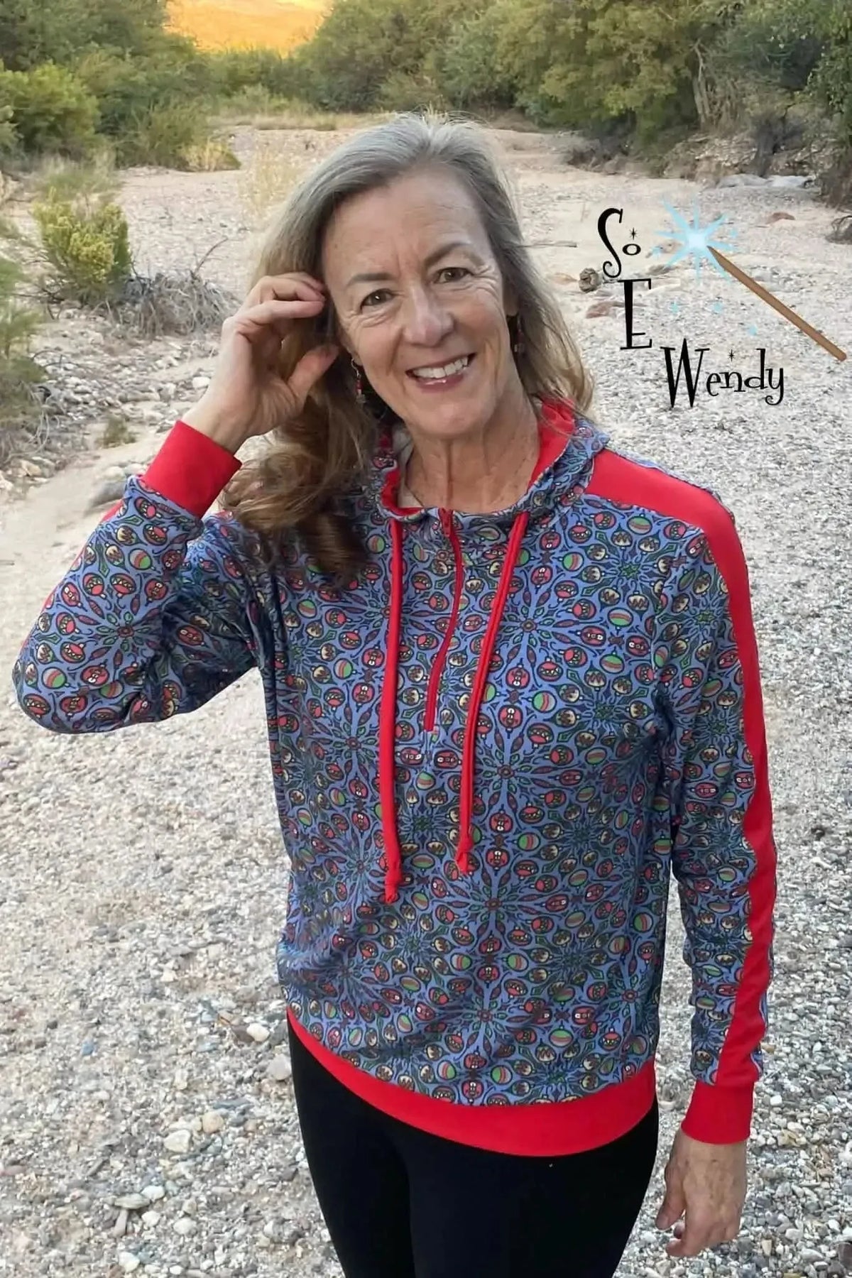 Woman modeling a navy blue hooded sweatshirt with red accents and floral print.