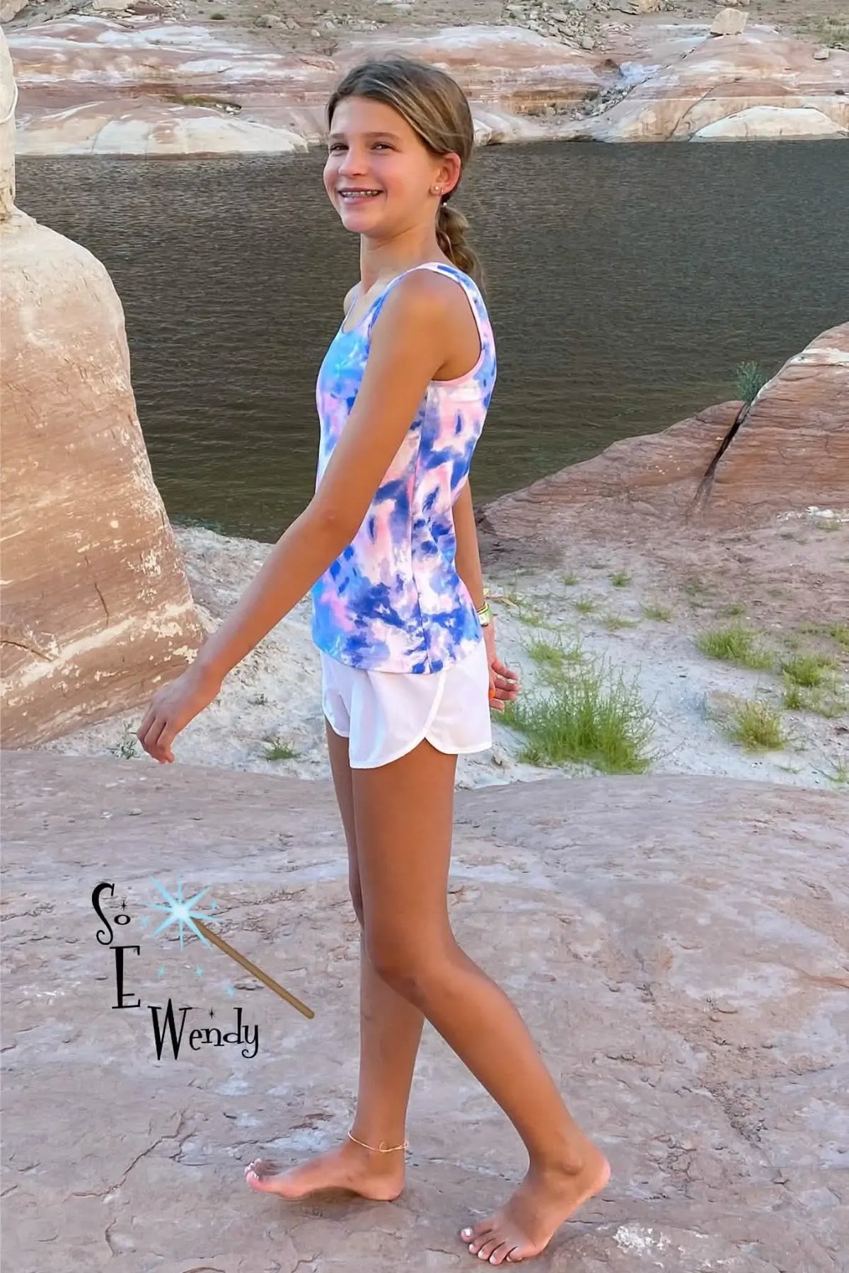 A girl wears a tie-dye tank top with pink, blue, and white colors.