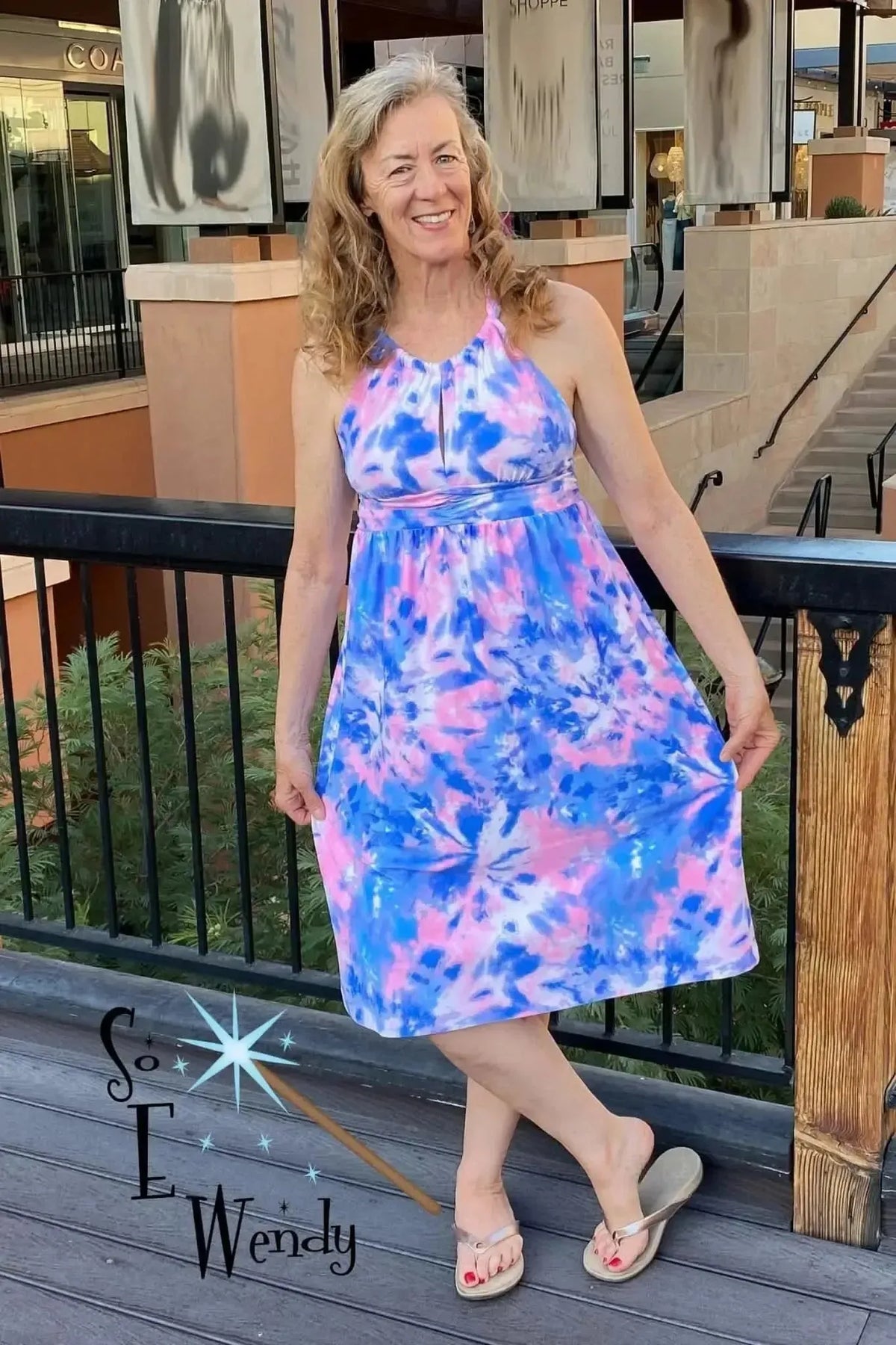 A woman wears a bubblegum tie-dye dress with vibrant pink and blue print.