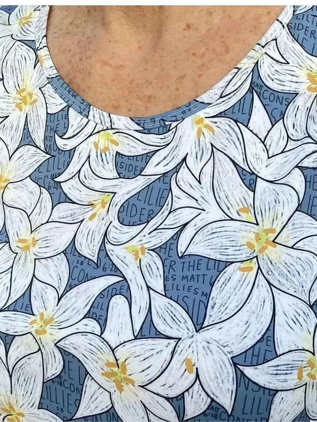 Blue fabric with a white lily floral print and faint text.