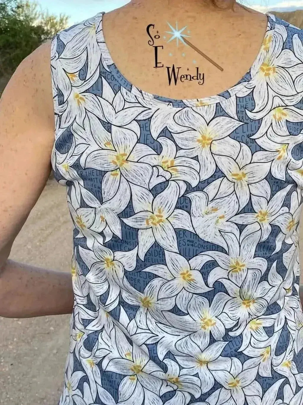 Blue lilies floral print fabric on a sleeveless top, worn by a model outdoors.