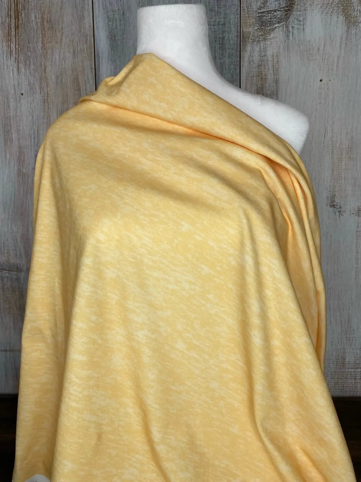 Yellow heather fabric draped over a white mannequin against a wooden background.