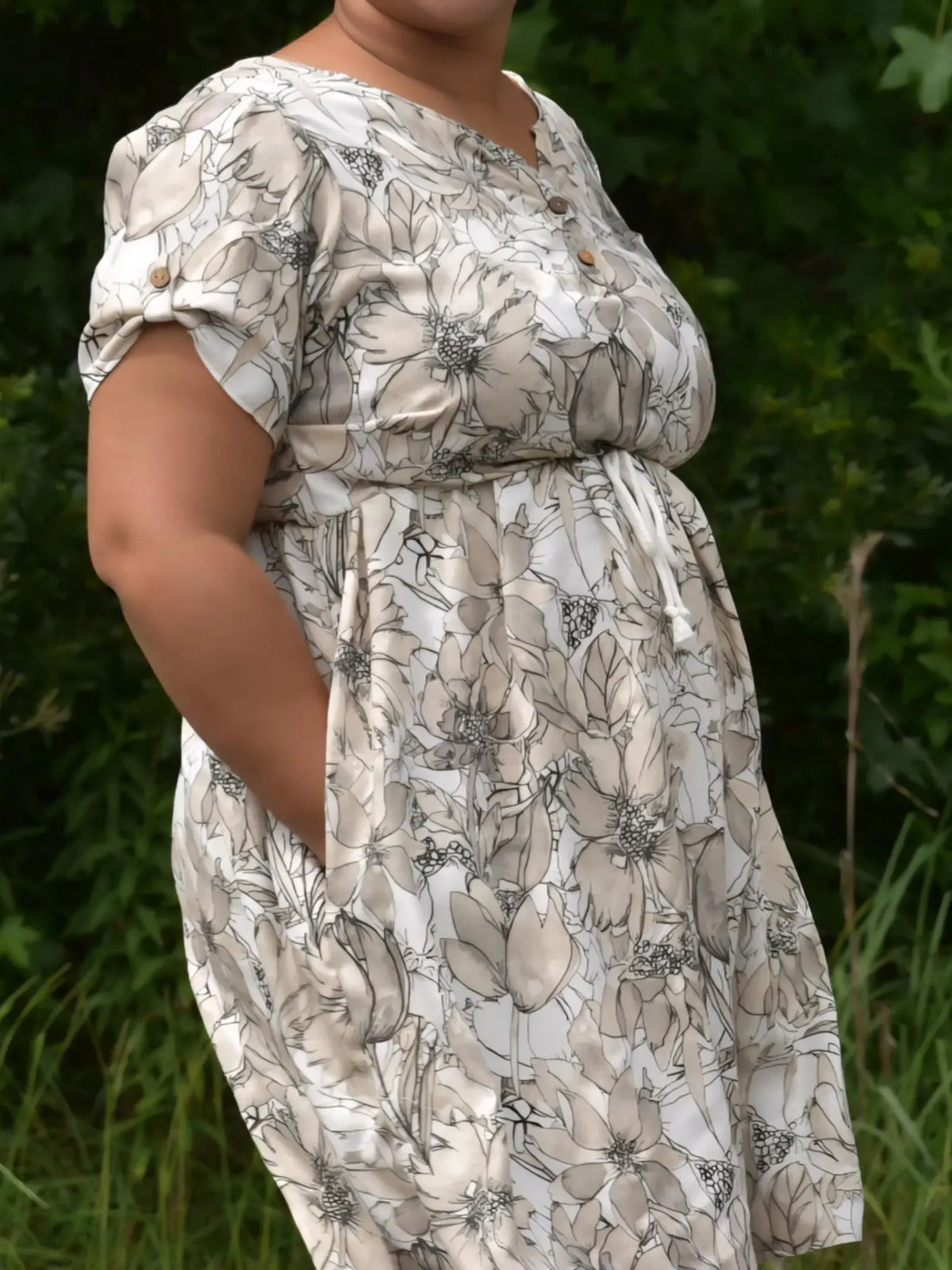 A person wears a floral dress with sepia-toned flowers and a drawstring waist.