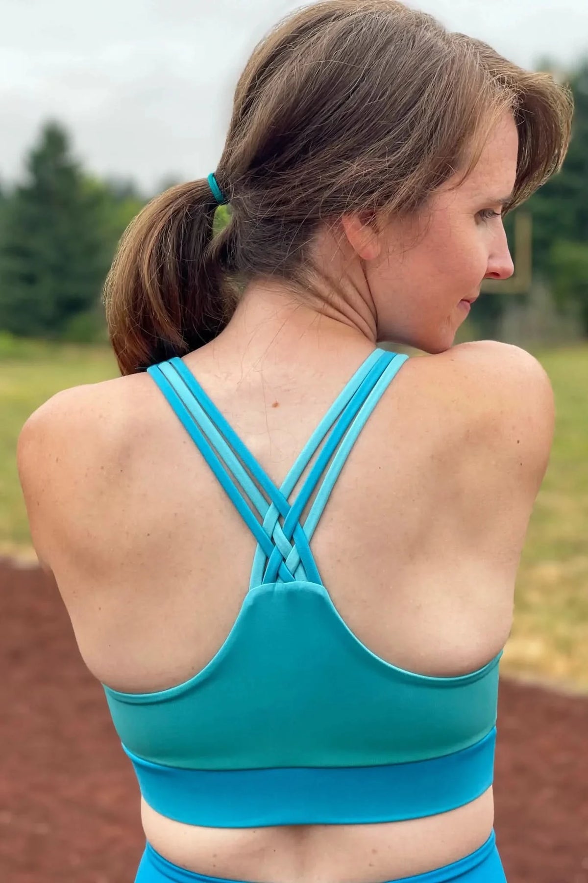 Woman in a teal and blue ombre sports bra with braided straps.