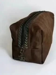 A brown zippered pouch with a decorative zipper pull is angled on a white background.