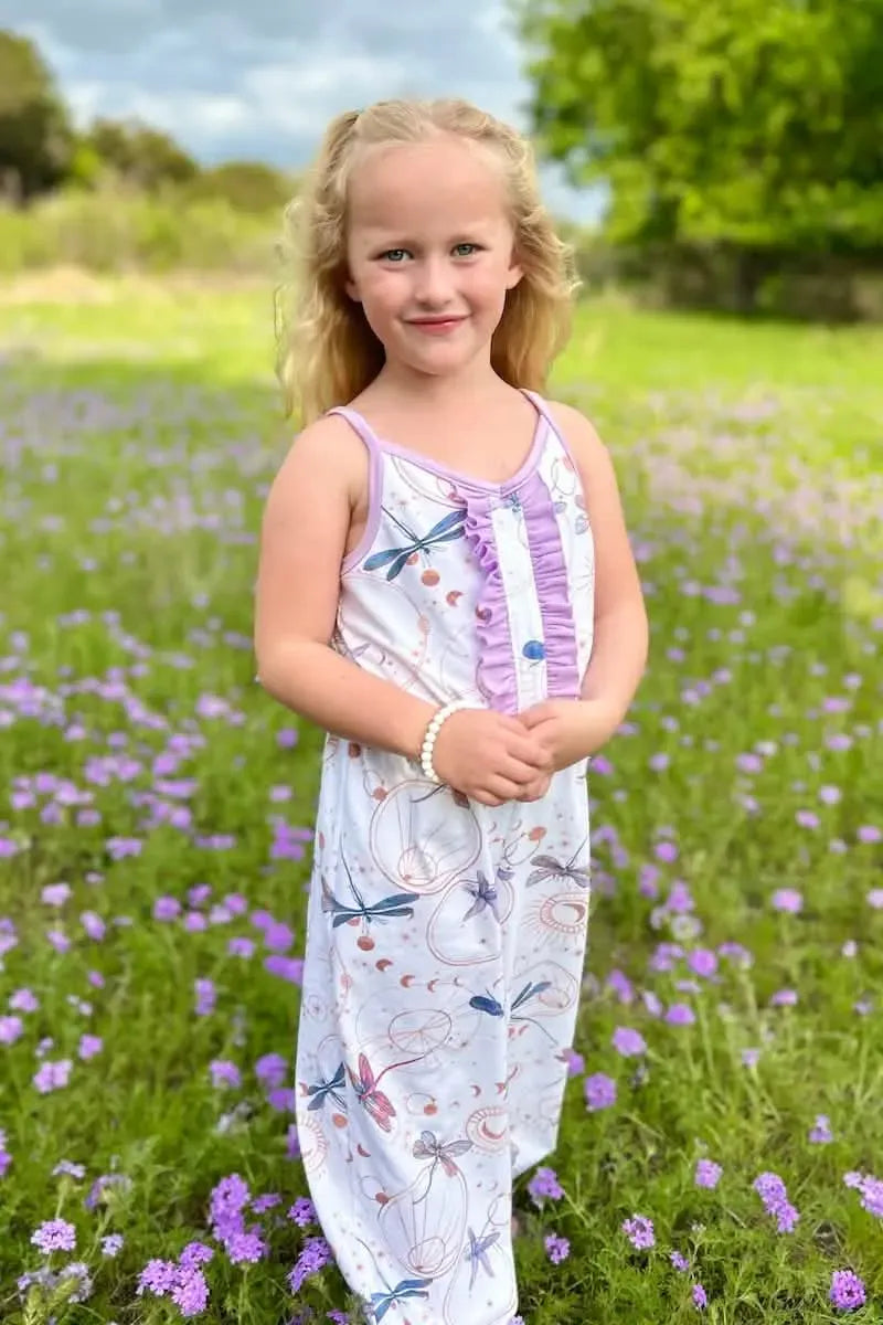 A young girl wears a white dress with a celestial dragonfly pattern.
