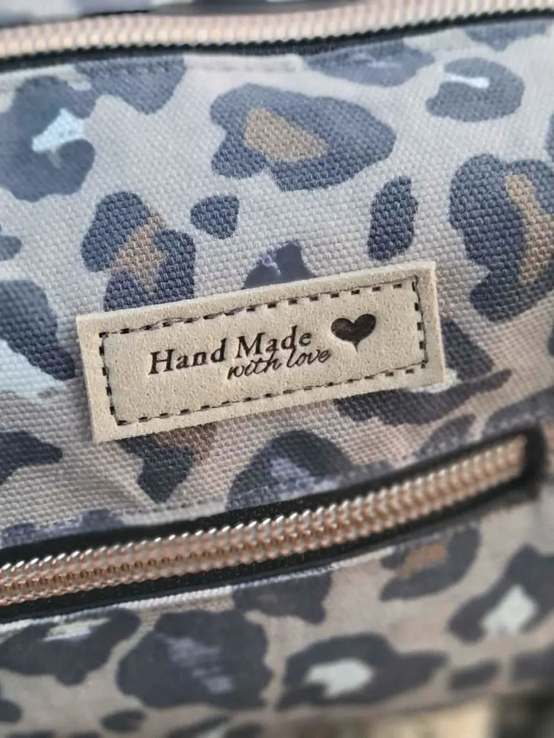 A close-up of a leopard print fabric bag with a "Hand Made with love" tag.