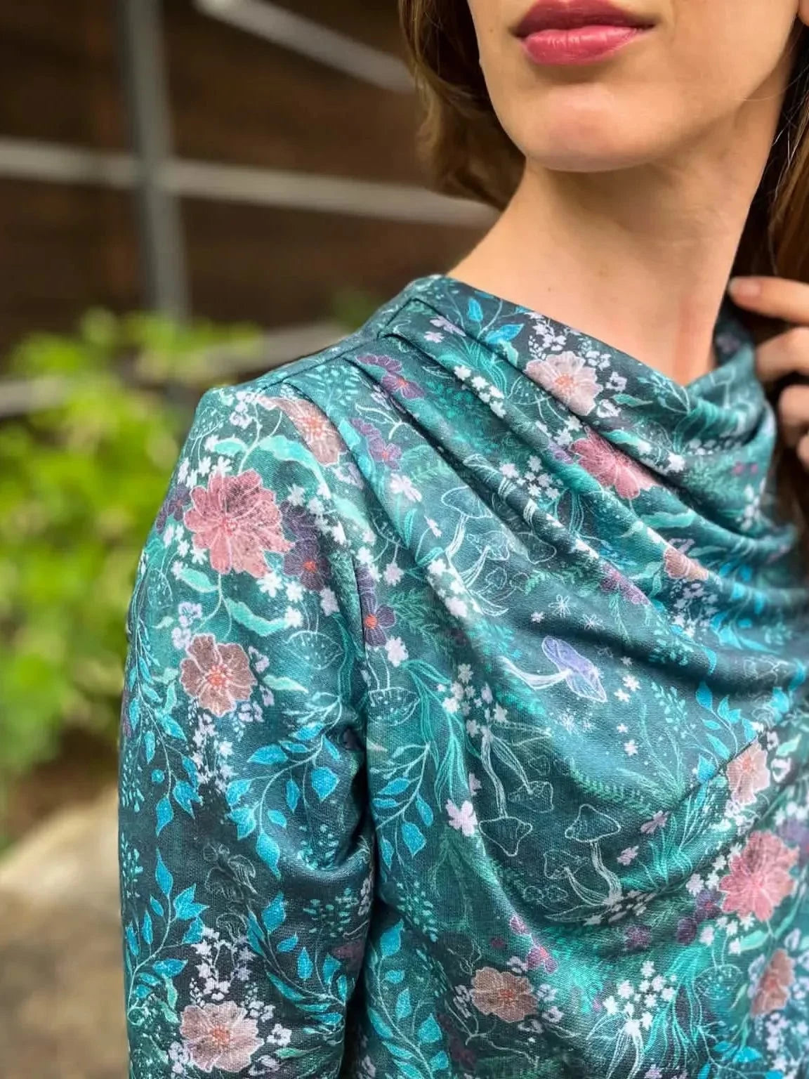 Teal woodland print fabric with pink flowers and mushrooms on a draped garment.