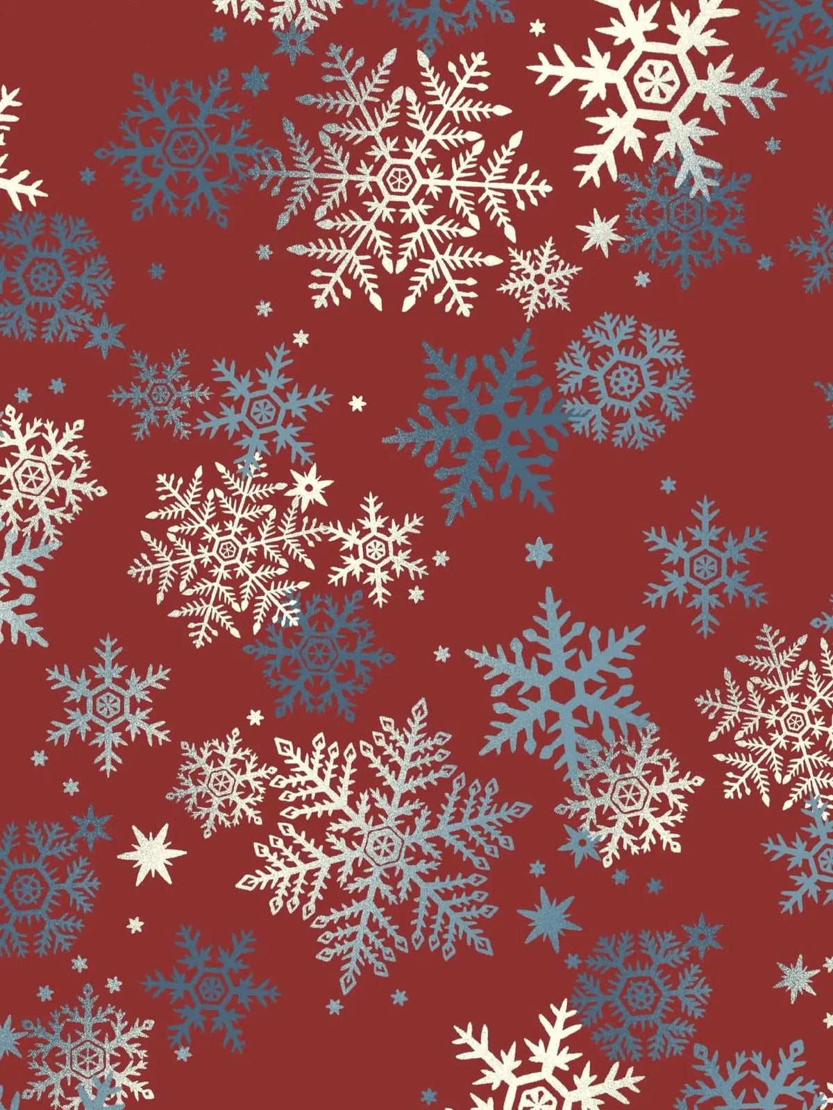 A red fabric with white and blue snowflakes of various sizes.
