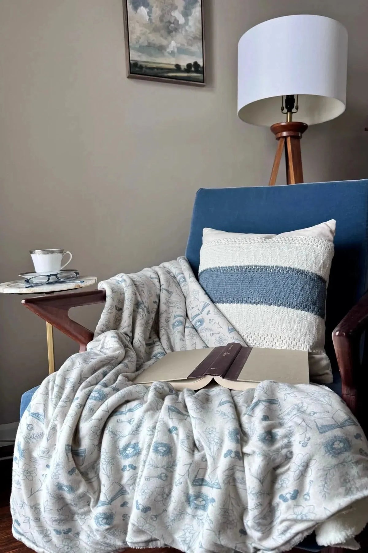 Blue floral toile print fabric draped over a chair with book and teacup.