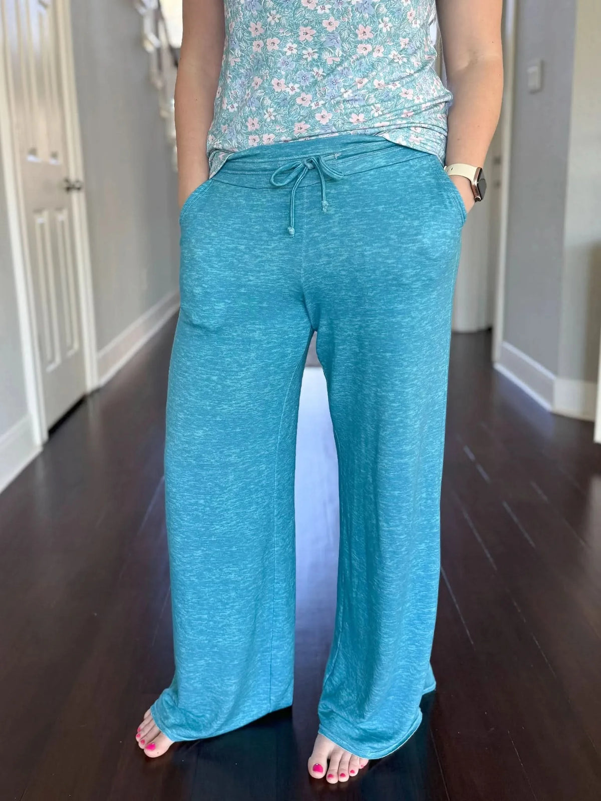 A person wears dark teal heather wide-leg pants with a floral top.