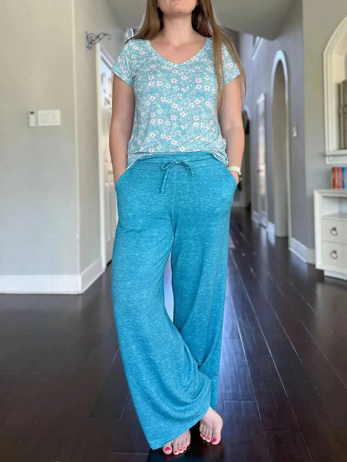 A woman models a floral top and dark teal heather wide-leg pants with a drawstring waist.