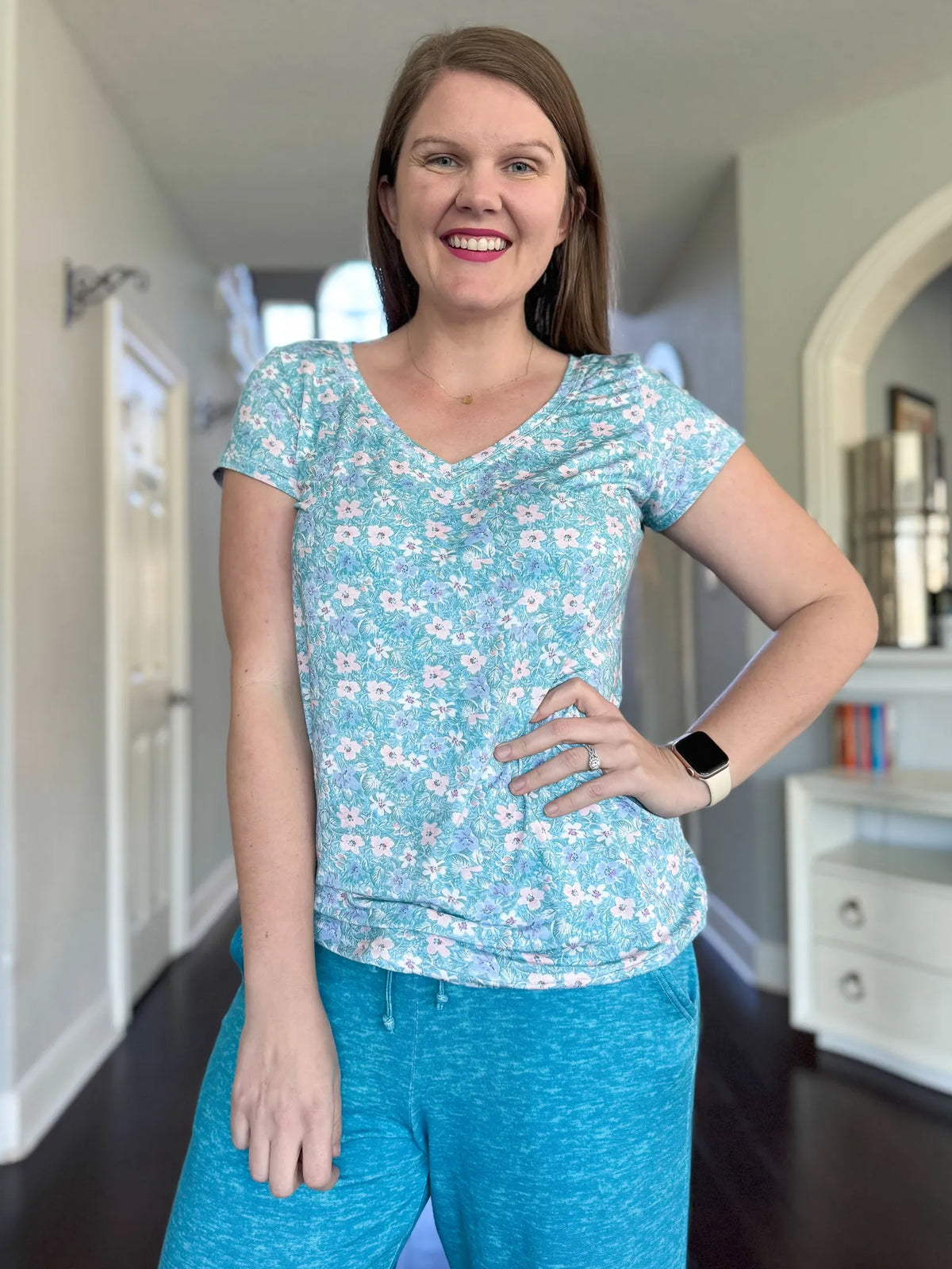 A woman wears a light blue floral v-neck shirt and matching sweatpants.