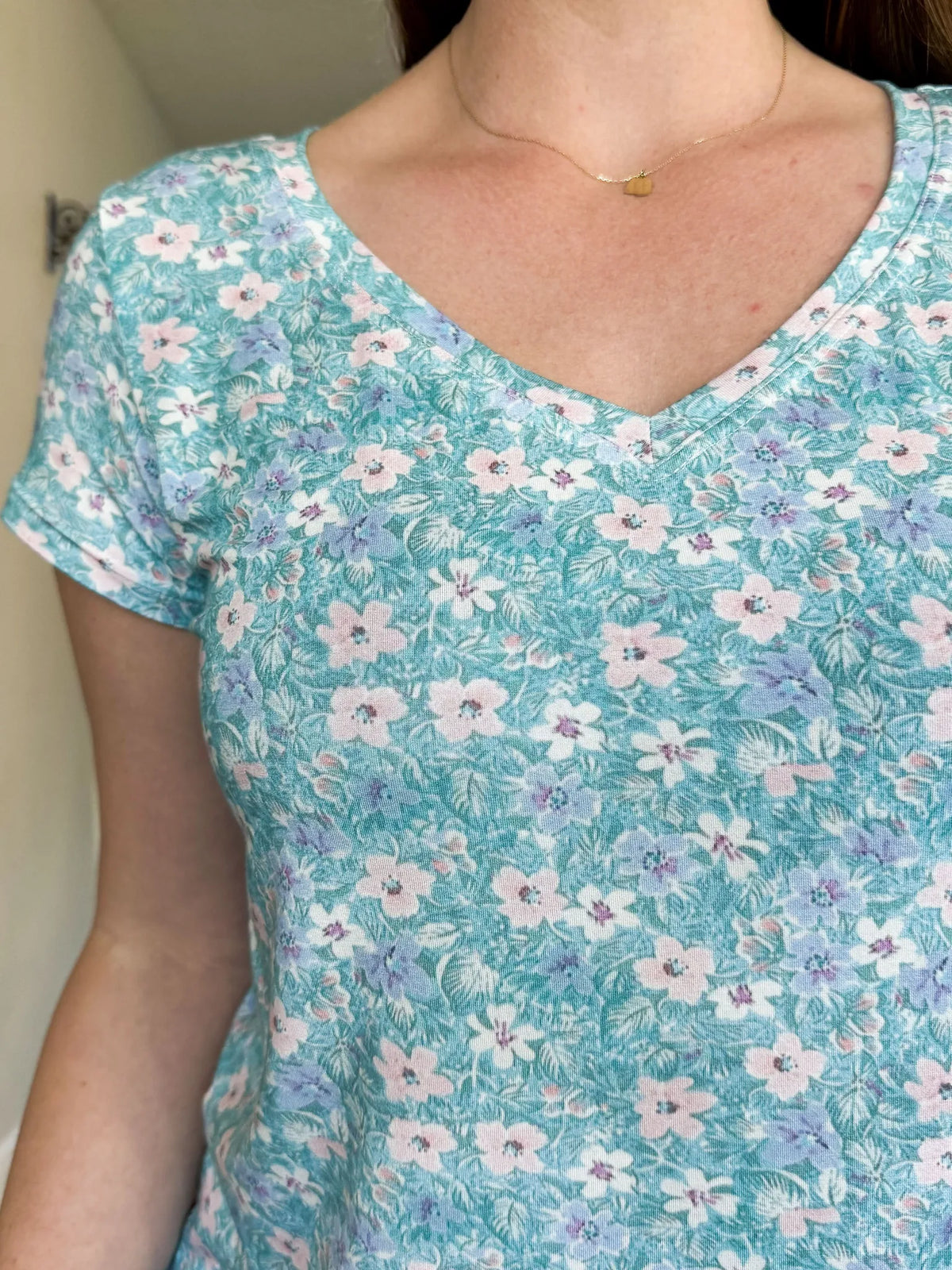 A person wearing a light blue floral print v-neck shirt.
