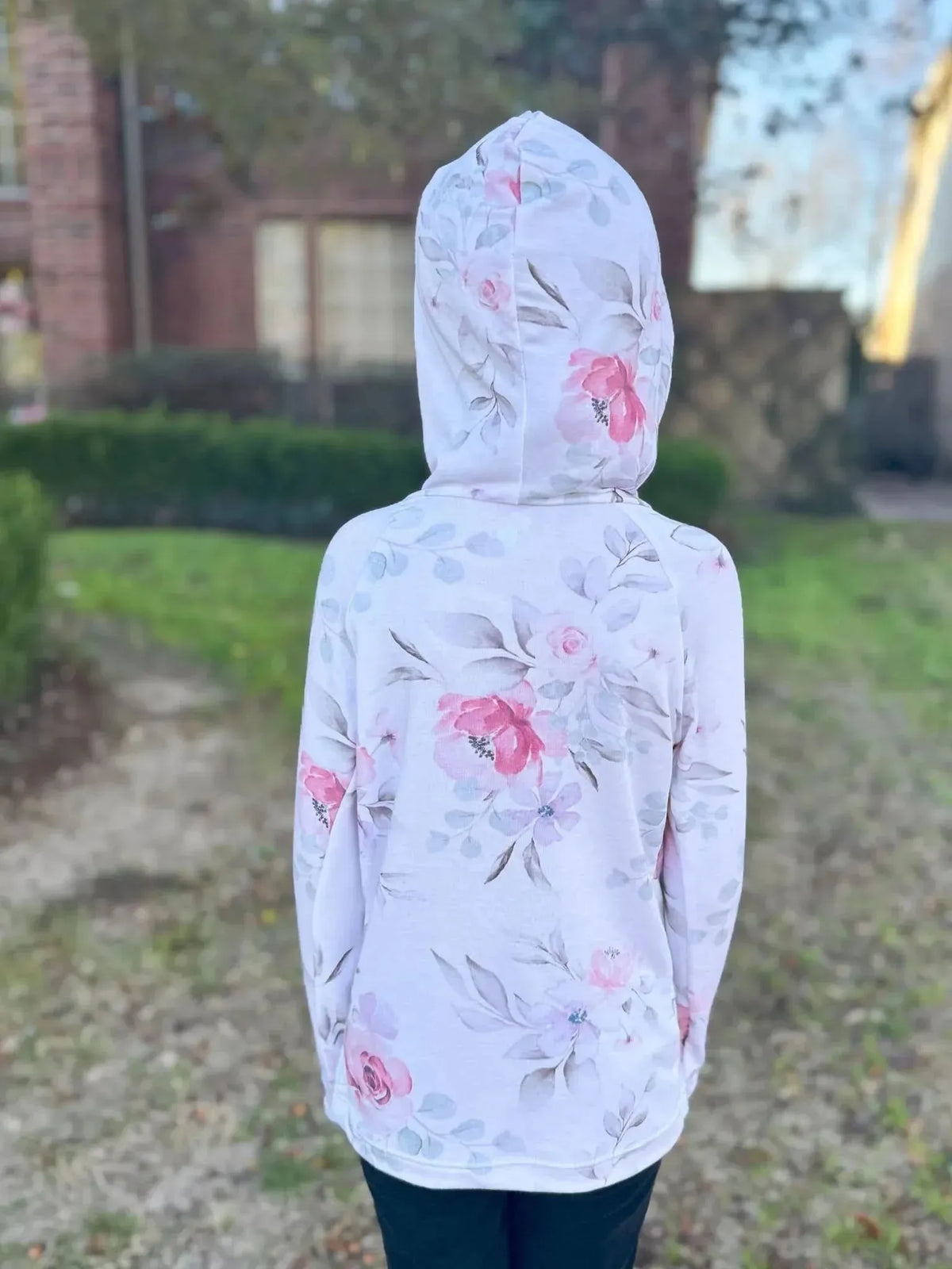 A person from behind wearing a pink watercolor floral hoodie.