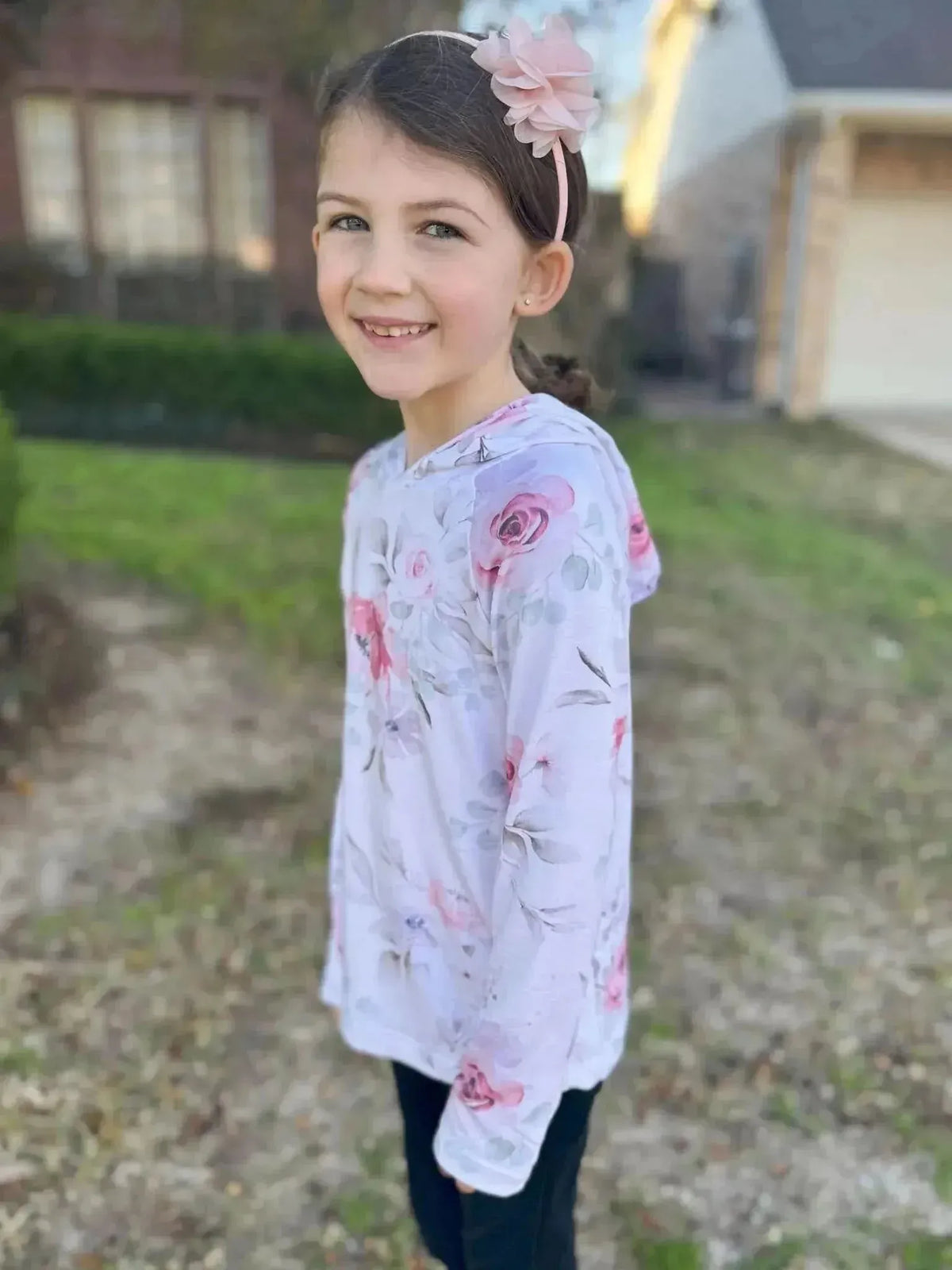 A young girl wears a long-sleeved shirt with a pink watercolor floral print.