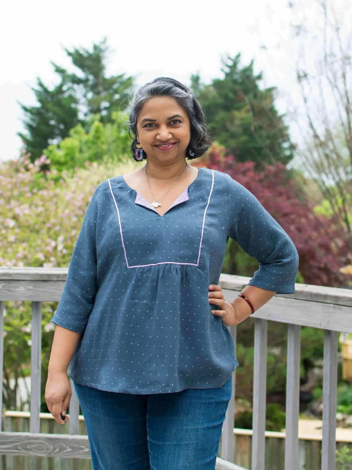Woman in a navy polka dot top with pink trim and blue jeans.