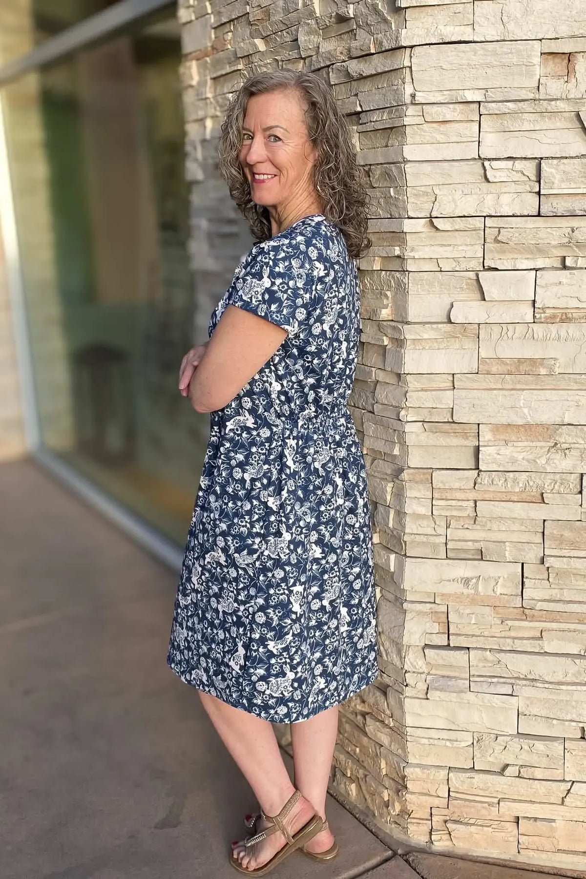 A woman in a navy blue dress with a white bunny and floral print smiles at the camera.