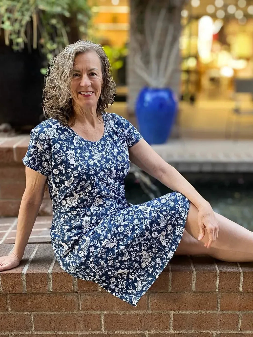 A woman in a navy blue dress with a white bunny and bramble pattern.