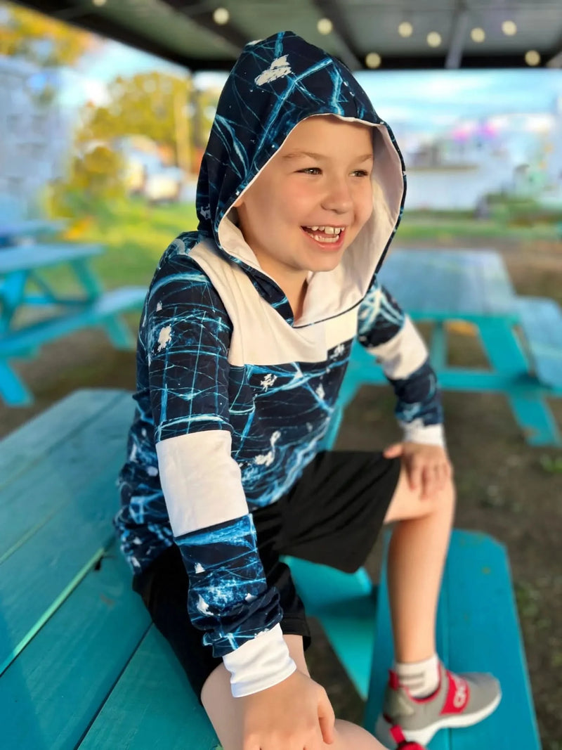 A young boy wears a navy blue hoodie with a cracked ice pattern.