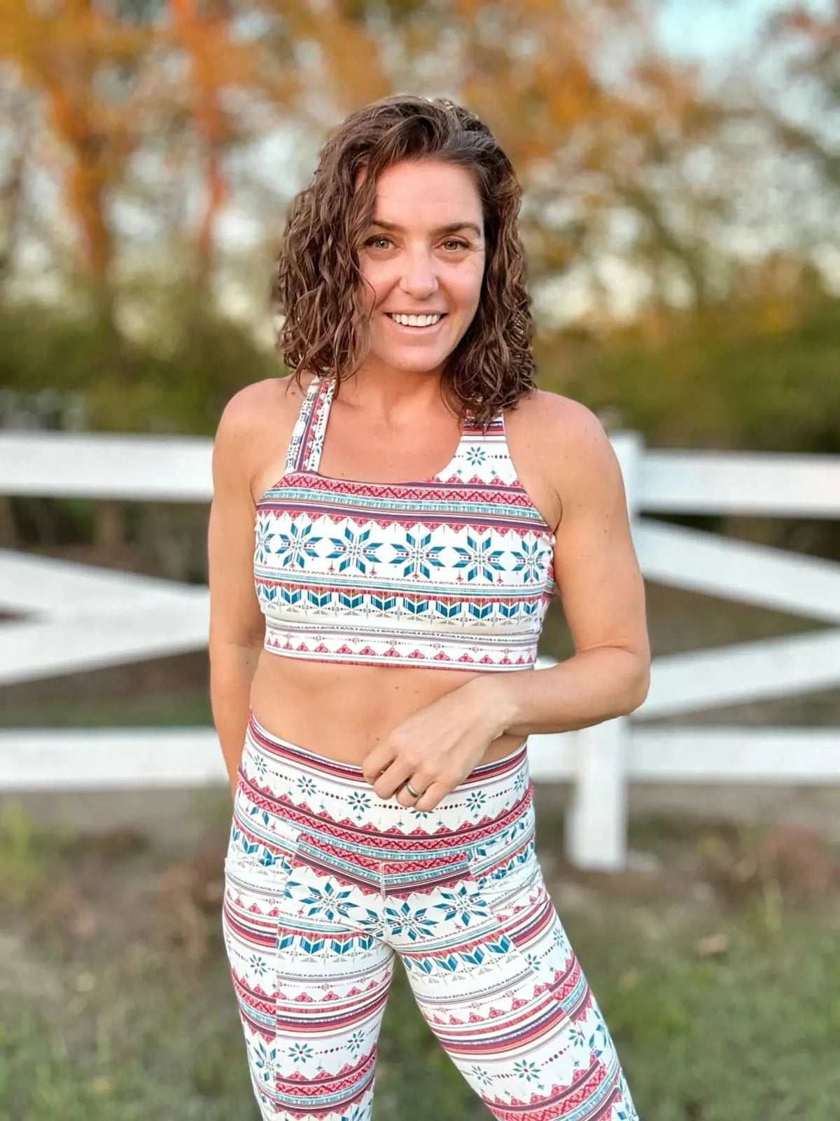 A woman smiles wearing a Frosted patterned sports bra and leggings set.