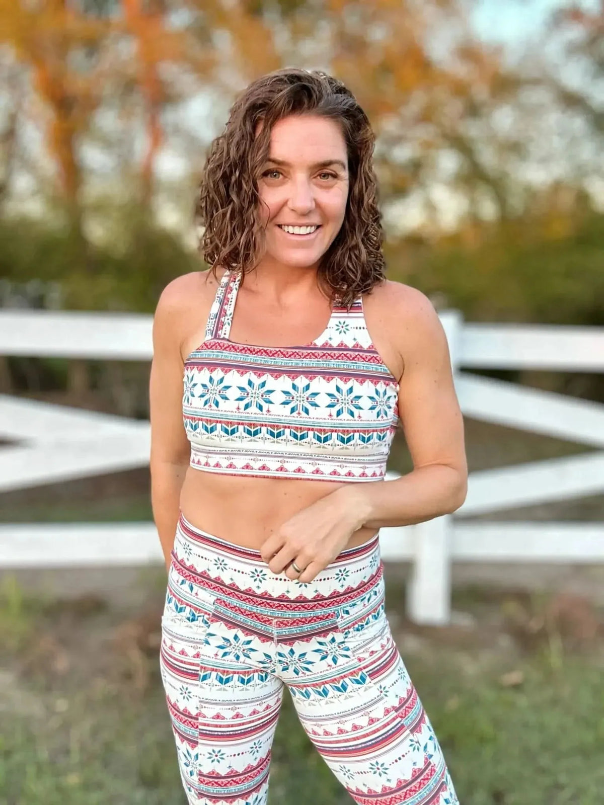 Woman modeling white athletic wear with red and blue Fair Isle snowflake pattern outdoors.
